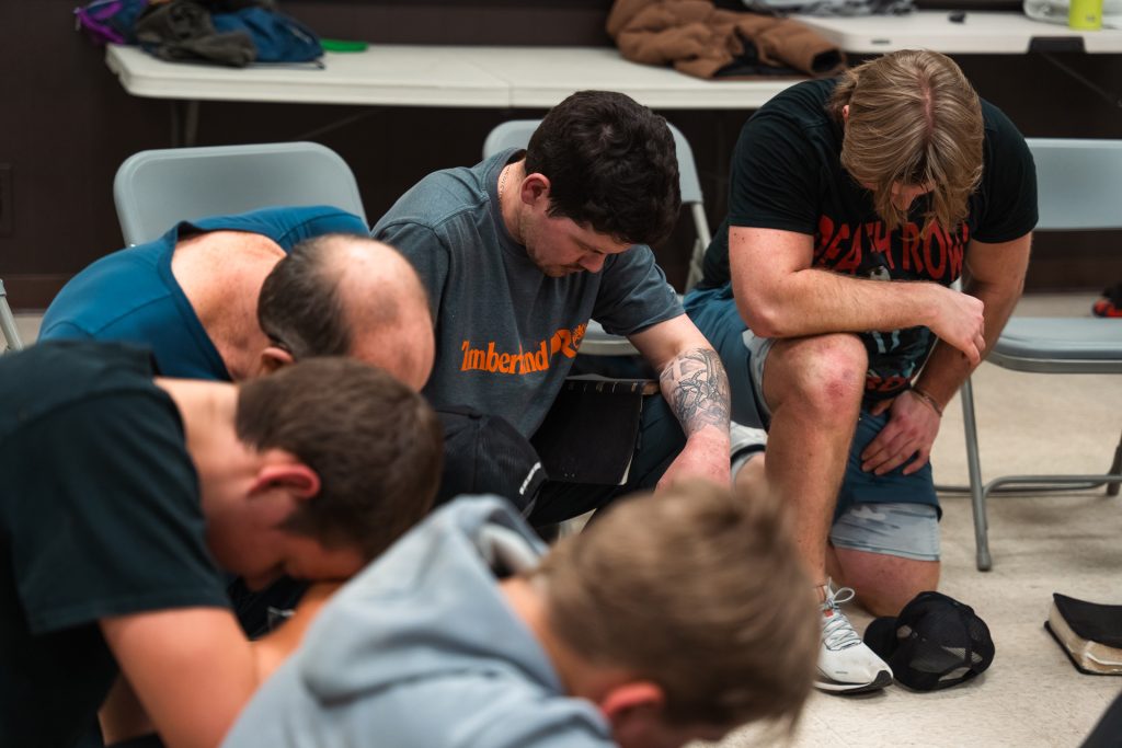 Christian men praying together for strength and faith
